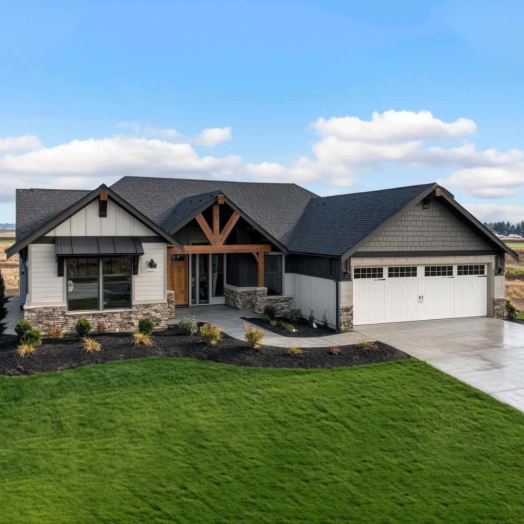 Modern single-family home with stone accents, large windows, and a landscaped yard, featuring a two-car garage and clear blue skies.